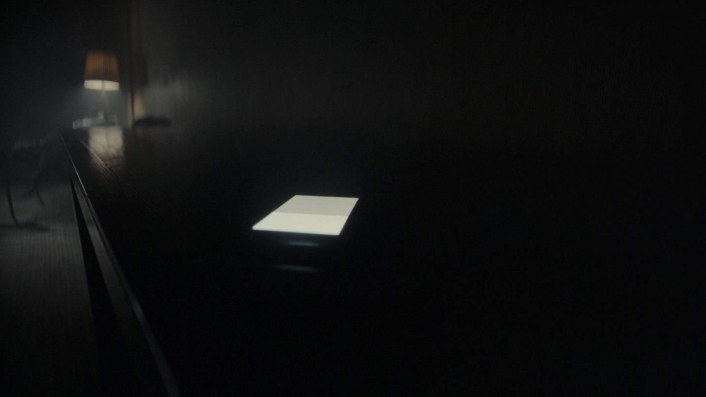 Tela de celular acesa no escuro, iluminando o rosto de quem segura